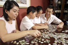 Family Of Four Working On Jigsaw Puzzle