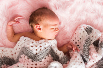 1 month old baby girl sleeping on pink rug with crochet blanket