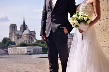 wedding couple with beautiful bouquet in front of the Notre Dame church in city of love, in Paris