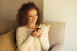 © Africa Studio - Young beautiful woman holding cup of coffee and sitting on sofa in the room