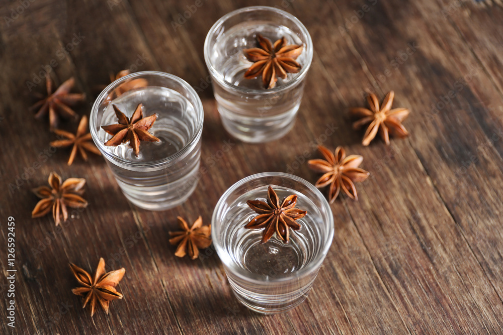 Vodka with anise on wooden background