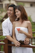 Couple standing side by side on balcony, smiling