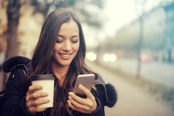 girl with hot drink and smartphone
