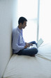© Alexander - Man at home, sitting on bed, using laptop