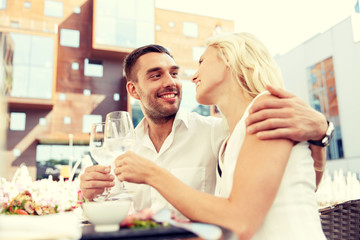 Wall Mural - happy couple drinking wine at open-air restaurant