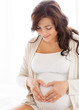 © Syda Productions - happy pregnant woman making heart gesture at home