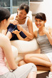 © Alexander - Three young women on sofa, talking