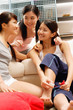 © Alexander - Three young women in living room, one holding nail polish bottle