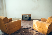 Pair Of Disused Sofa Chairs In Front Of Broken TV