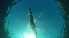 UNDERWATER LOW ANGLE: Athletic Man Swimming Crawl In Blue Ocean On Sunny Day
