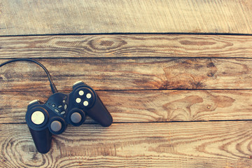 Video game controller on old wooden background. Toned image. Top view. 