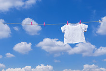 Plain White T- Shirt Hanging On Clothes Line Against Blue Sky
