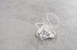 White headphones with tangled wire lying on stone table. Concept of audio, sound or mobile accessory.
