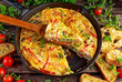 © grinchh - Frittata made of eggs, potato, bacon, paprika, parsley, green peas, onion, cheese in iron pan. on wooden table.