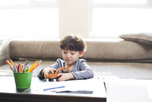 Little Boy Playing With A Toy When Doing Homework