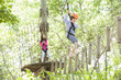 © Blue Jean Images - Little girls playing in tree top adventure park