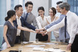© Blue Jean Images - Confident business people stacking hands in meeting room