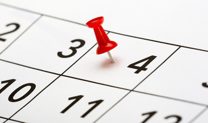 Pin on the date. The fourth day of the month is marked with a red thumbtack. Focus point on the red pin.