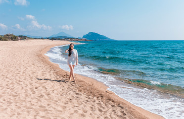 Wall Mural - beautiful brunet woman walking on a beach in white dress