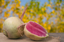 One Whole And Sliced Watermelon Radish On A Wooden Table With Blurred Garden Background