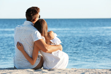 Sticker - Happy couple sitting on sand on seashore