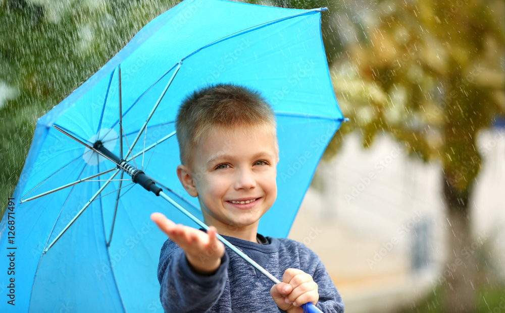 Portrait of boy with blue umbrella in rain
