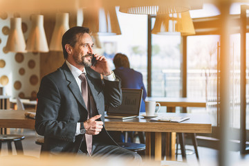 Wall Mural - Joyful businessman communicating on smartphone