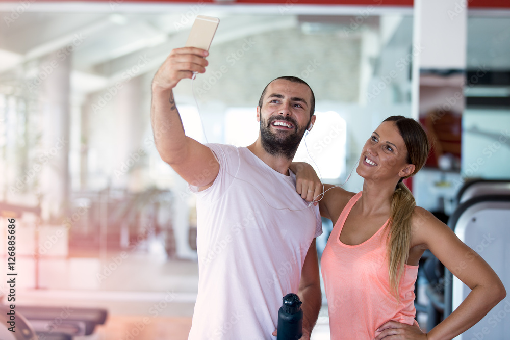 Young couple taking a sefie in a gym - obrazy, fototapety, plakaty 