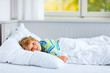 © Irina Schmidt - happy little kid boy after sleeping in bed in colorful nightwear