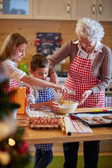 Wall Mural - children and grandmother preparing Xmas cookies.