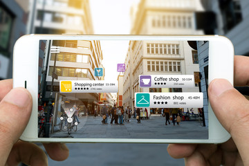 Augmented reality marketing concept. Hand holding smart phone use AR application to check relevant information about the spaces around customer. City and flare light background