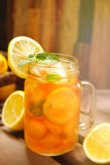 Canvas Print - Glass jar of iced tea with lemon slices and mint on wooden board, closeup