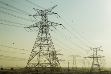 High voltage power lines in Dubai. Voltage electricity pylons in the desert.