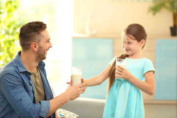 Wall Mural - Father and daughter with glasses of fresh milk at living room