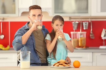 Wall Mural - Father and daughter drinking fresh milk at kitchen