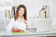 © Stocked House Studio - Smiling nutritionist writing medical records with fresh fruit on foreground