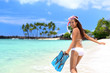 Happy beach vacation girl having fun doing snorkel watersport activity in caribbean ocean. Asian woman enjoying swimming in tropical destination vacation travel holidays on white sand beach.