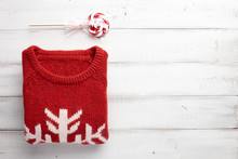 Winter Holiday Knitted Sweater And Christmas Lollipop On White Wooden Background.