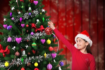 Girl in santa hat decorating christmas tree