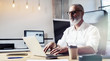 © SFIO CRACHO - Middle age financial analyst wearing a classic glasses and working at the wood table with exchange markets.Stylish bearded businessman using laptop on workplace. Horizontal,blurred.