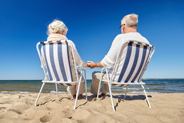 Wall Mural - senior couple sitting on chairs at summer beach