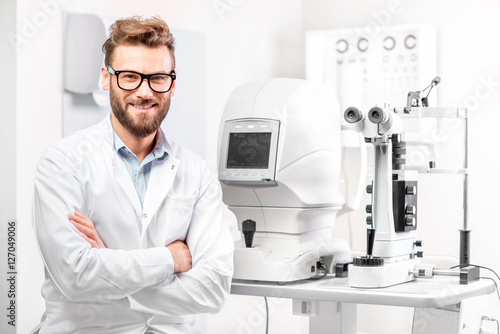 Fotografía Portrait of handsome eye doctor sitting with ophthalmologic device in the cabine