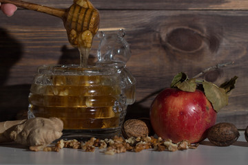 When is could outside , you can make delicious warm tea with ginger and jar of honey and nuts. Apple on the table. Honey flow from honey spoon. The leaf on the red Apple