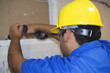 © Freestocker - Construction worker with yellow helmet using an electric screwdriver