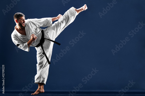 Dekoracja na wymiar  karateka-w-kimonie-uderza-stopa-na-niebieskim-tle