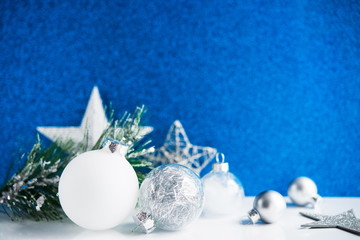 Wall Mural - silver and white xmas ornaments on blue bokeh background. merry christmas card. winter holiday theme