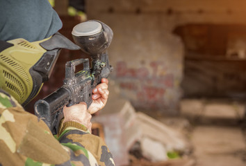 Paintball gamer with gun in camouflage uniform