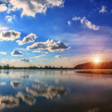 Fototapeta Tęcza - breathtaking scenery. Blue sky with clouds. reflection in water, for design .Colorful majestic sunset with a halo of sunlight. picturesque scene. use as background