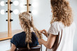 © Cookie Studio - Female hairdresser making hairstyle to blonde girl in beauty salon.