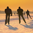 Ice Skaters on frozen lake at orange sunset